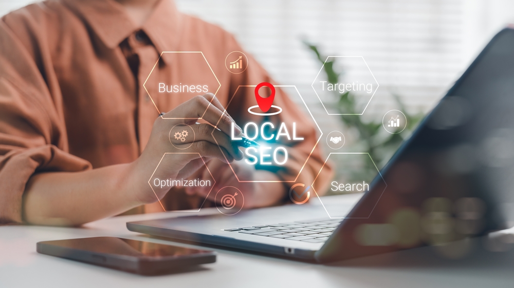 Business owner using a laptop with local SEO, targeting and search icons
