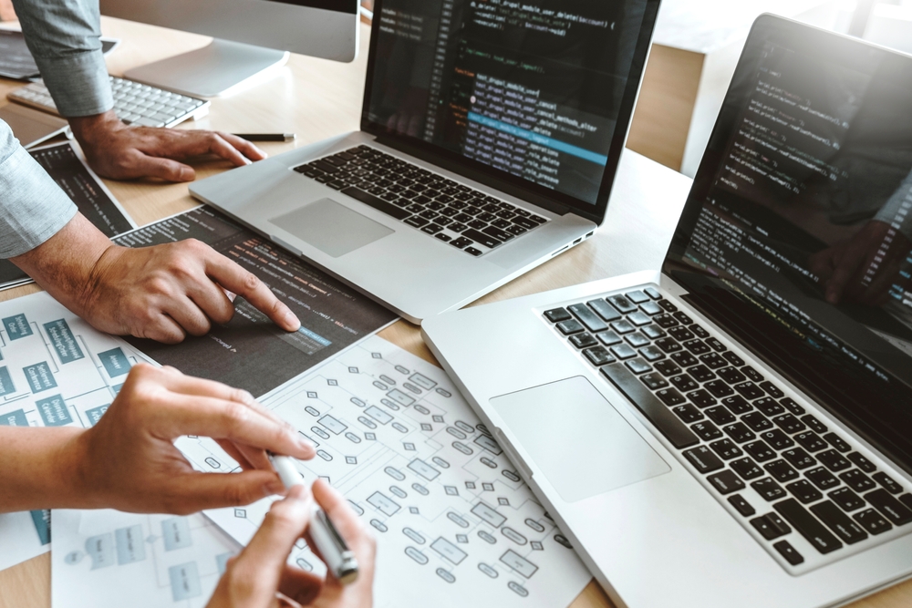 Web developers reviewing website code and site structure plans on laptops